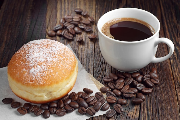 Berliner donuts with cup of hot coffee on dark wooden table