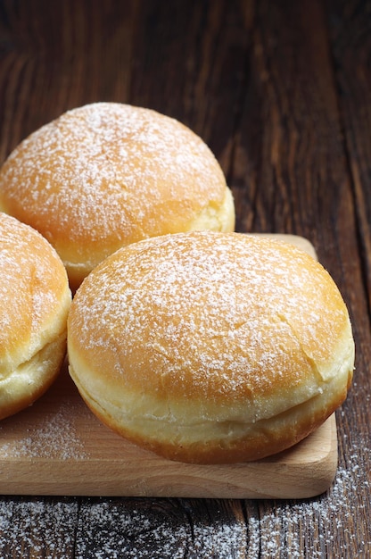 Berliner donuts with powdered sugar on wooden table