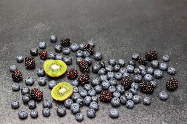 Berries of blackberries and blueberries two halves of kiwi on black