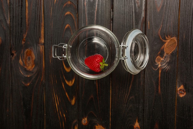 Berries fresh strawberries in a glass jar on a wood background