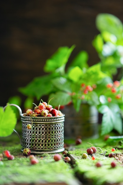 Berries from the forest. Bone and strawberry berries on old wooden background with moss