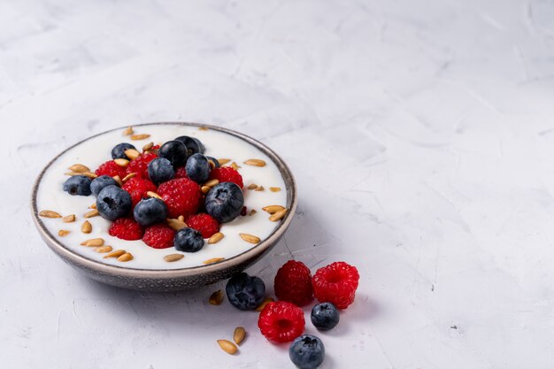 berries yoghurt in ceramic bowl on white table