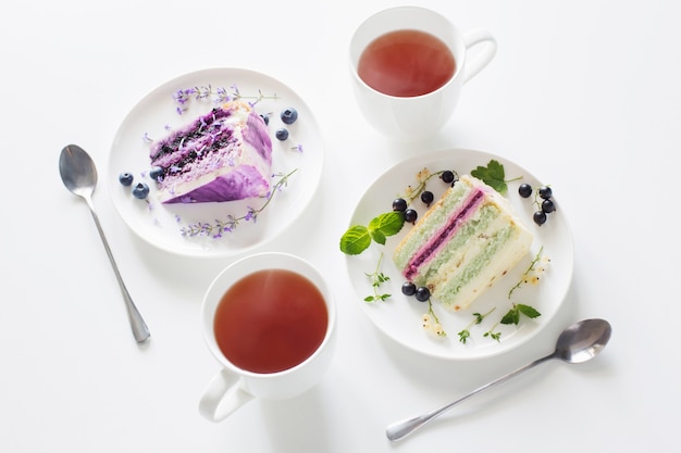 Berry cheesecakes and two cups of tea on  white table