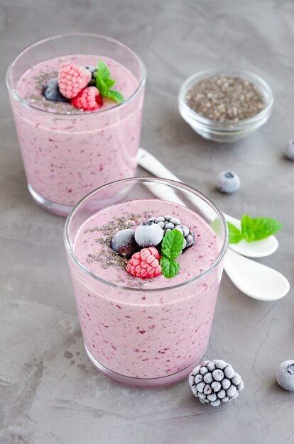 Berry smoothies of yogurt, chia seeds and frozen berries in a glass on a dark