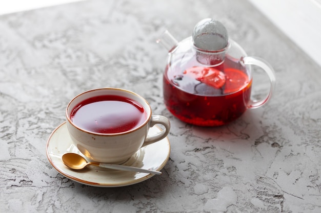 Berry tea in glass teapot on gray surface