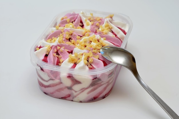 Berry vanilla ice cream in a plastic tray and a spoon beside