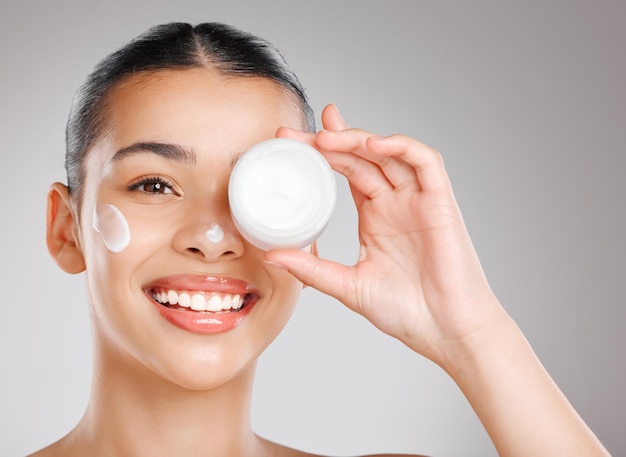 The best beauty product in my bathroom cabinet Studio shot of an attractive young woman applying moisturiser to her face against a grey background