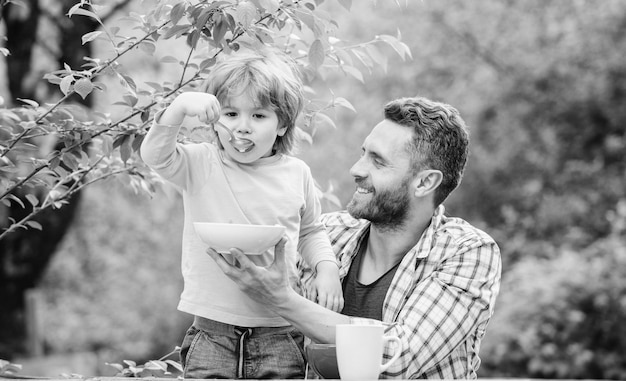 Best day ever healthy food and dieting Dairy products happy fathers day Little boy with dad eat cereal father and son eating outdoor family dinner time Morning breakfast Vegetarian diet