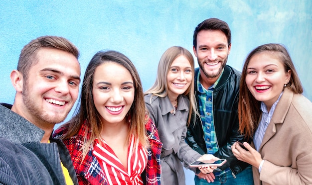 Best friends taking selfie wearing four seasonal clothes