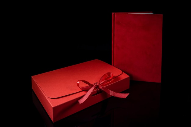 Best gift for men Man gift concept Red notebook with red gift box on black background Copy space Valentine's day wedding birthday and special occasion gift concept Copy space for text