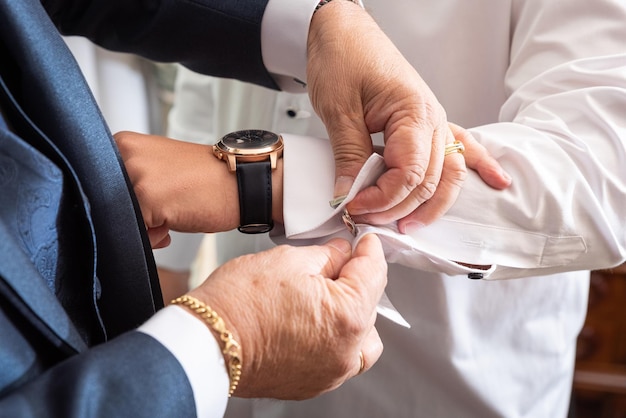 The best man helping the groom with the cufflinks on his wedding day