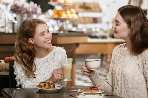 Best times together. Two beautiful happy girls having coffee and desserts together at the local cafe