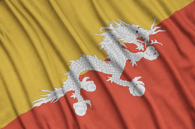 Bhutan flag is depicted on a sports cloth fabric with many folds.