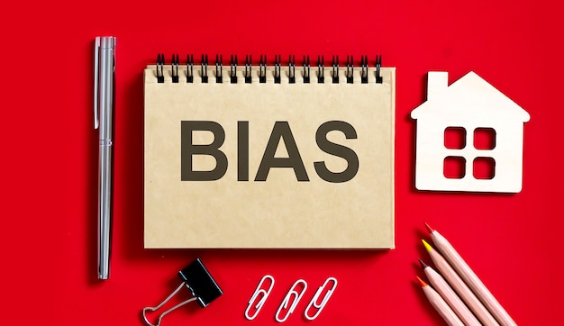 BIAS text written on a notebook with pencils and office tools and model wooden house