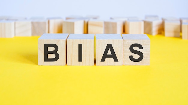 Photo bias word on wooden blocks lyinging on the yellow table. business concept toy blocks with letters around. selective focus