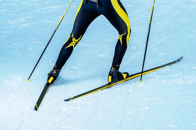 Photo biathlete or crosscountry skier back with legs and equipment detail of legs skis and poles