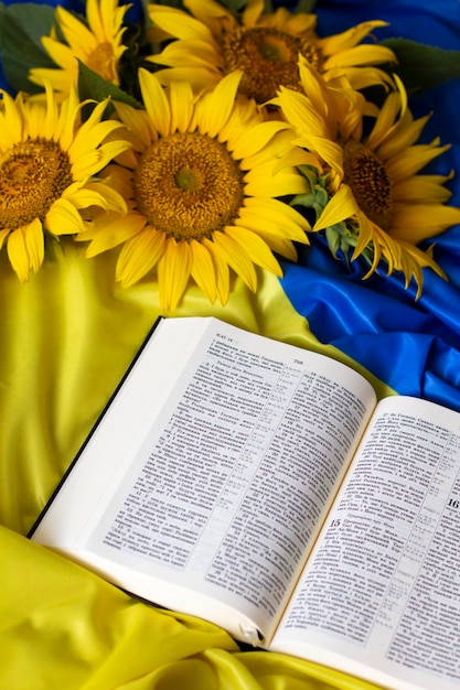 Bible Holy Writ and sunflowers on background of flag of Ukraine