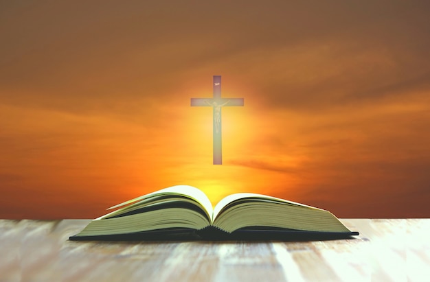 Bible open on wood floor with Jesus cross on multi color background