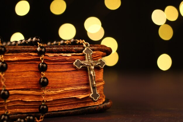 Bible and rosary close-up with bokeh lights