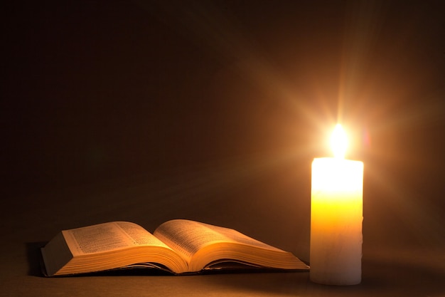 A bible on the table in the light of a candle