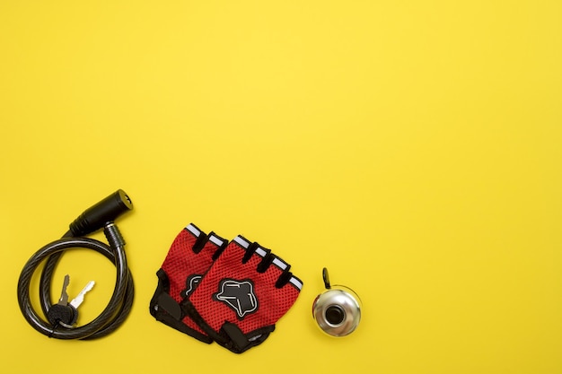 Bicycle lock gloves and a bell on a yellow background with copy space