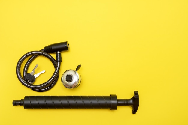 Bicycle lock with keys bell and pump on yellow background with copy space