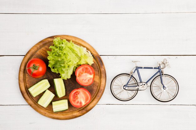 Bicycle model and fresh vegetables on white wooden desk