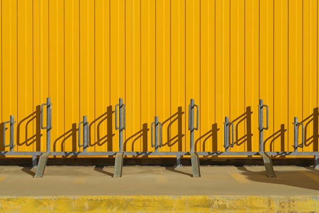 Bicycle parking near a bright yellow profiled metal wall fence or warehouse idea background for a screen or design articles