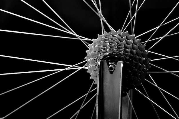 Bicycle repair The rear wheel is on a stand on a black background Rim and cassette closeup Black and white image Wheel truing stand Bicycle photographed in the studio