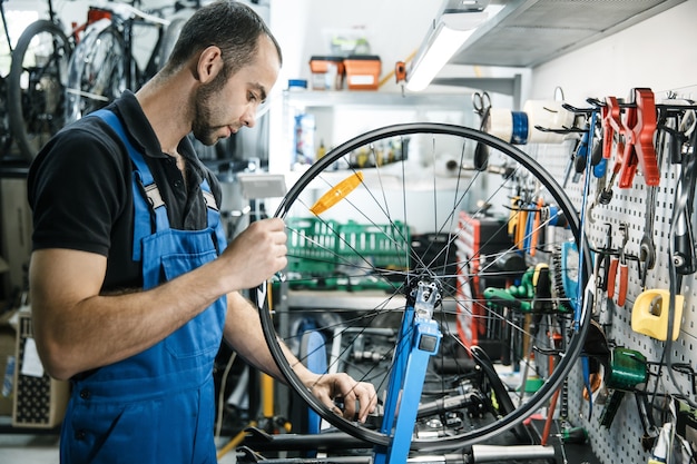 Bicycle repair in workshop, man works with wheel