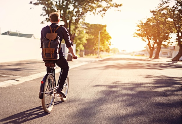 Bicycle transport and back of man in road with lens flare for exercise commute and cycling in morning Travel city and male cyclist on bike for eco friendly traveling carbon footprint and journey