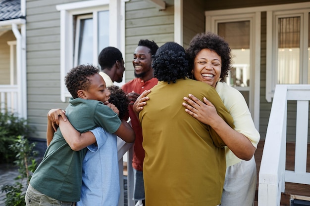 Big african american family embracing outdoors welcoming guests for party