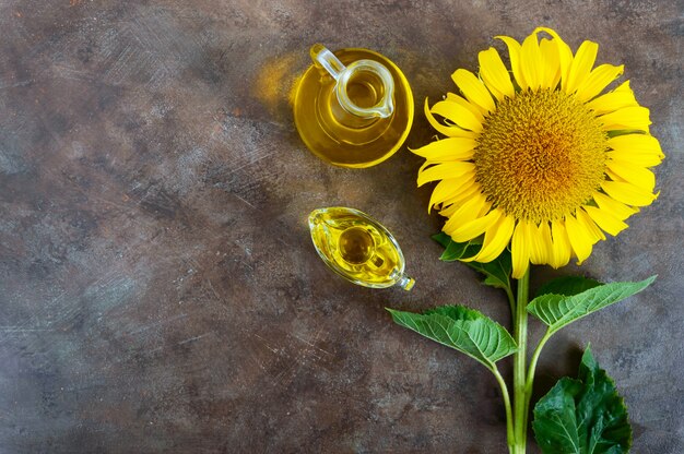 Big beautiful sunflower and bottle of oil on a vintage background. Agriculture for oil production. Autumn background with a sunflower. Free space for your project.