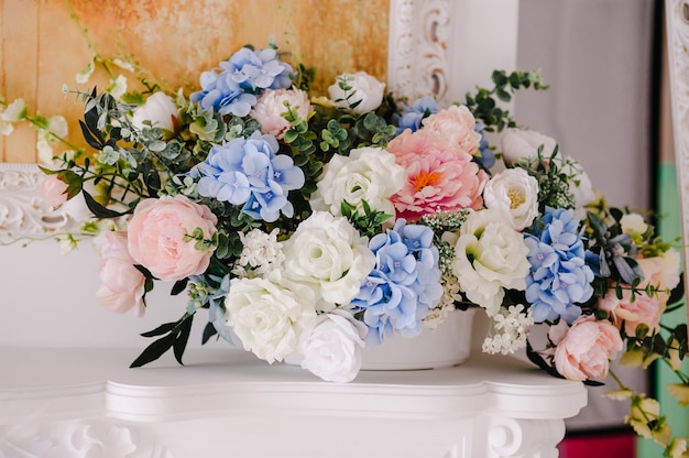 Big bouquet of fresh flowers, pink, blue hydrangeas, white roses and greenery in vase. Wedding flowers, bridal bouquet closeup. Home decor on table, vintage style. Decoration objects.