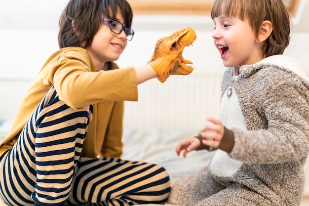 Big brother playing with a toddler sibling at home with a dinosaur  coming up with an interesting game Good relationships between family members concept