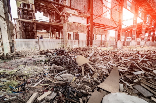 Big bunch of old rubbish on the background of a ruined plant Pile of wooden pieces lays on a dirty floor Environment pollution concept