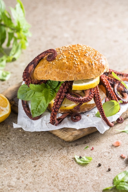 Big burger with octopus and lemon Large sandwich stuffed with seafood American fast food concept