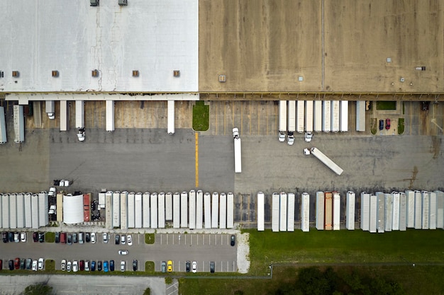 Big corporate shipment center with many cargo semi trucks unloading and uploading retail products for further retail shipment Global market concept