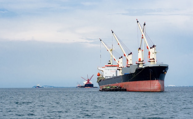 Big crane in the industrial ship in the ocean and mountain in island background