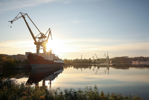 Big cranes and vessel at shipyard on sunny day