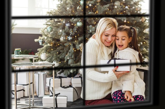 Big family with three children celebrating Christmas at home. Festive dinner at fireplace and Xmas tree. Parent and kids eating at fire place in decorated room. Child lighting advent wreath candle.