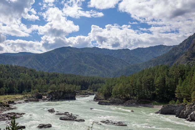 A Big fast-flowing wide and full-flowing mountain river. Large rocks stick out of the water.