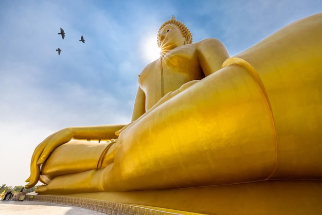 Big golden Buddha statue and blue sky over the sun light background