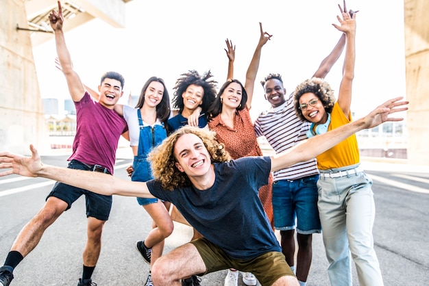 Big group of happy friends stands on city street with raised arms together people