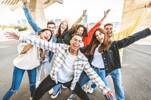 Big group of happy friends with arms up smiling at camera together