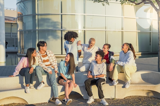 Big group of happy teenage friends talking in a bench in the street of the student campus