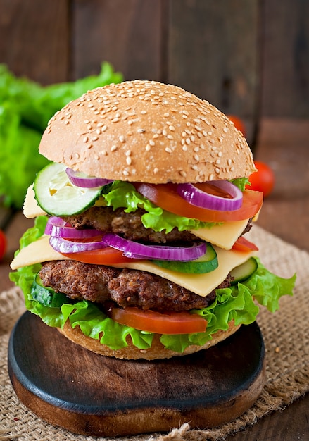 Big juicy hamburger with vegetables and beef on a wooden table in rustic style