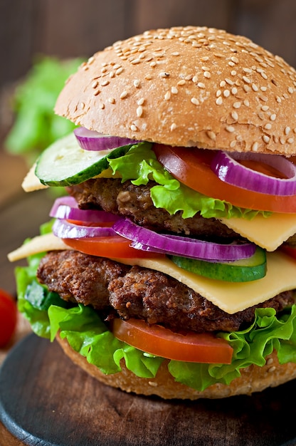 Big juicy hamburger with vegetables and beef on a wooden table in rustic style