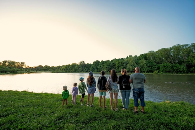 Big and large family against lake in sunrise Six children Parents and kids