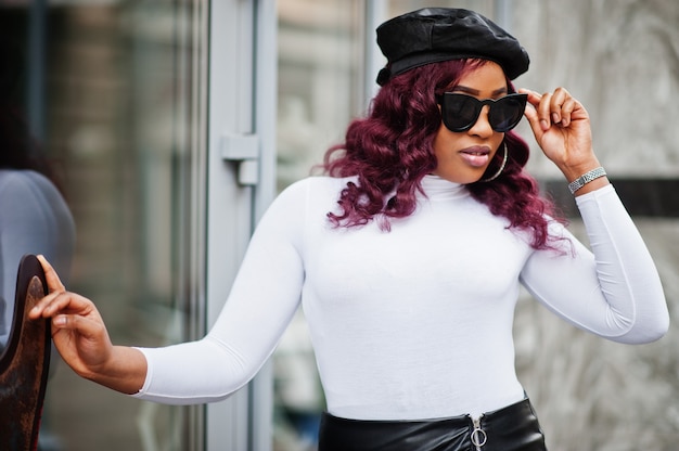 Big mama plus size african american model in black sunglasses, beret and leather skirt posed outdoor.